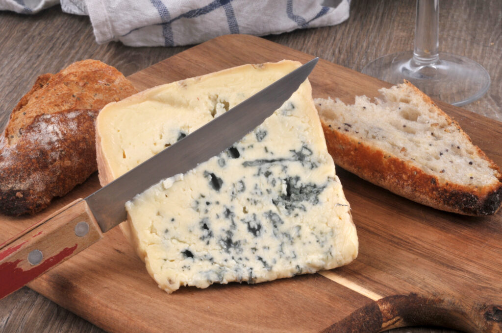 Morceau de Bleu d'Auvergne sur une planche à découper avec du pain et un couteau 