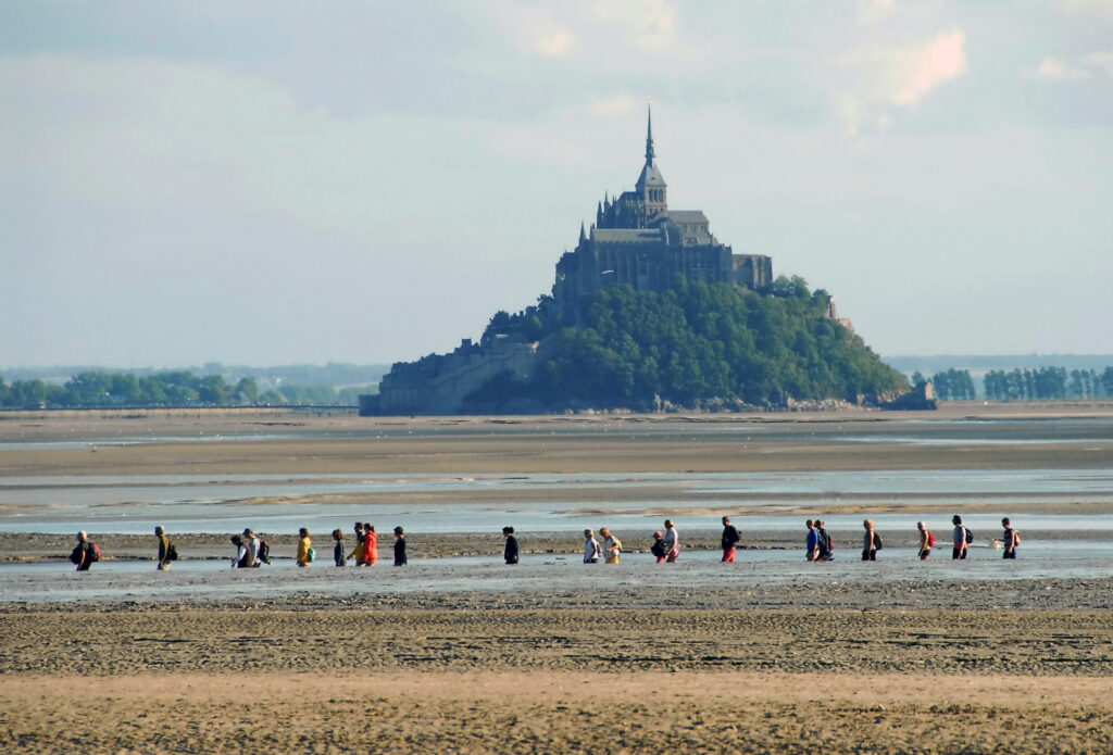 Groupe de personnes traversant la baie du Mont-Saint-Michel à marée basse