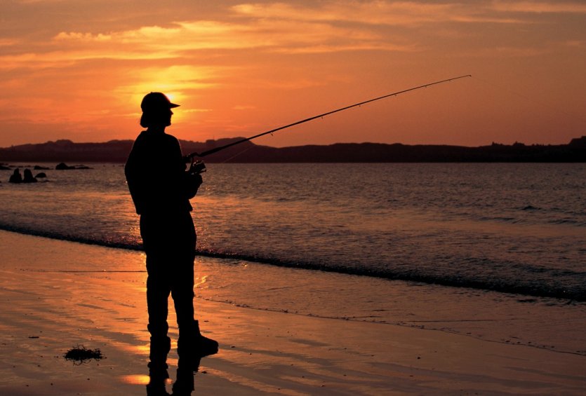 Pêcheur sur la plage au soleil couchant.