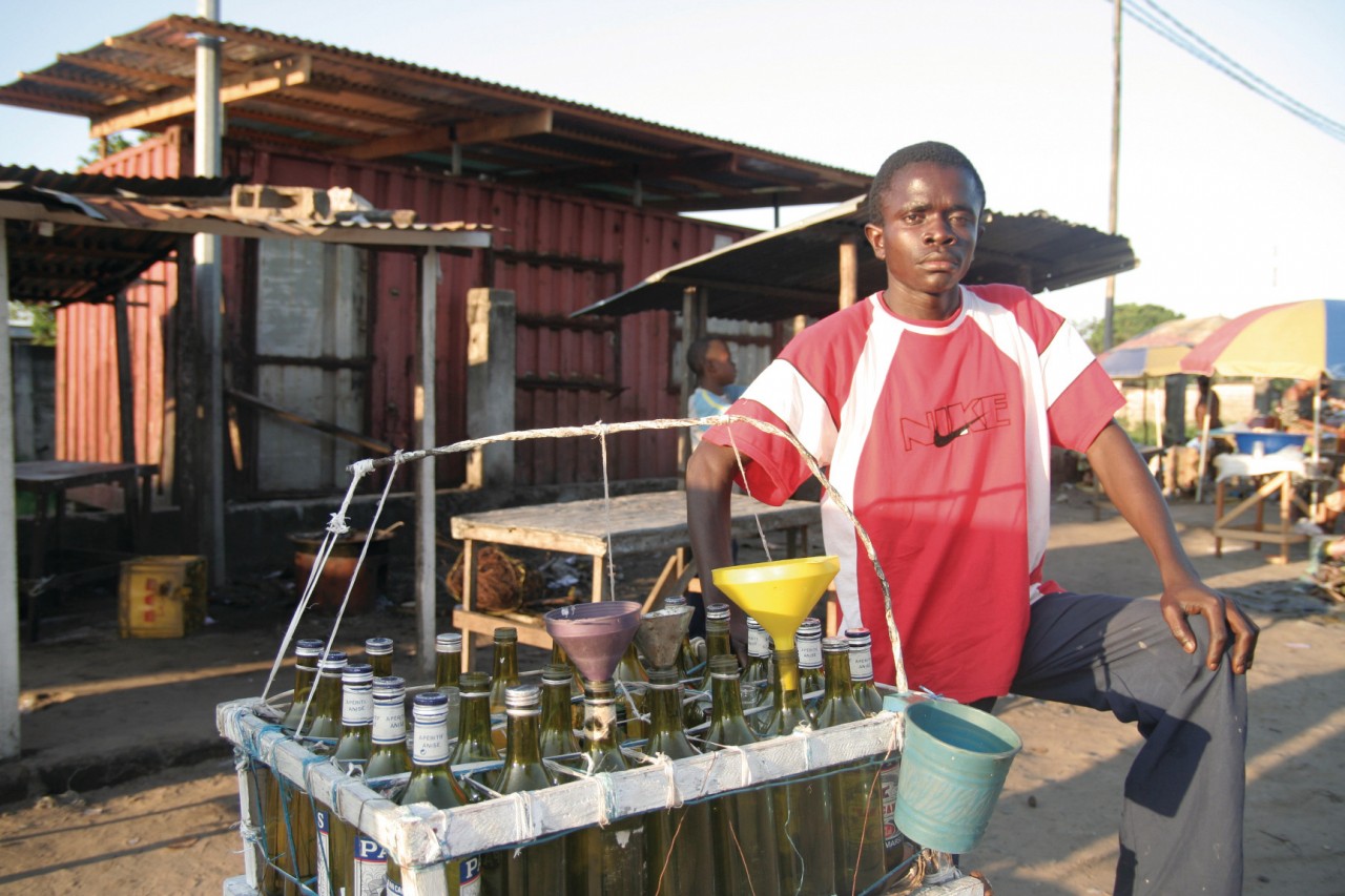 Revendeur d'essence devant sa marchandise.